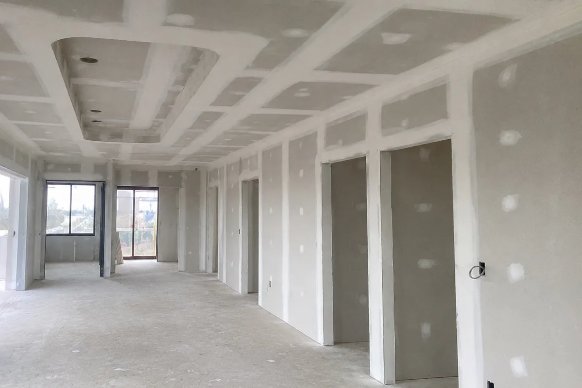 Interior of a new build lined and set by ReachOut, with a bulkhead ceiling detail and freshly jointed plasterboard walls and doorways